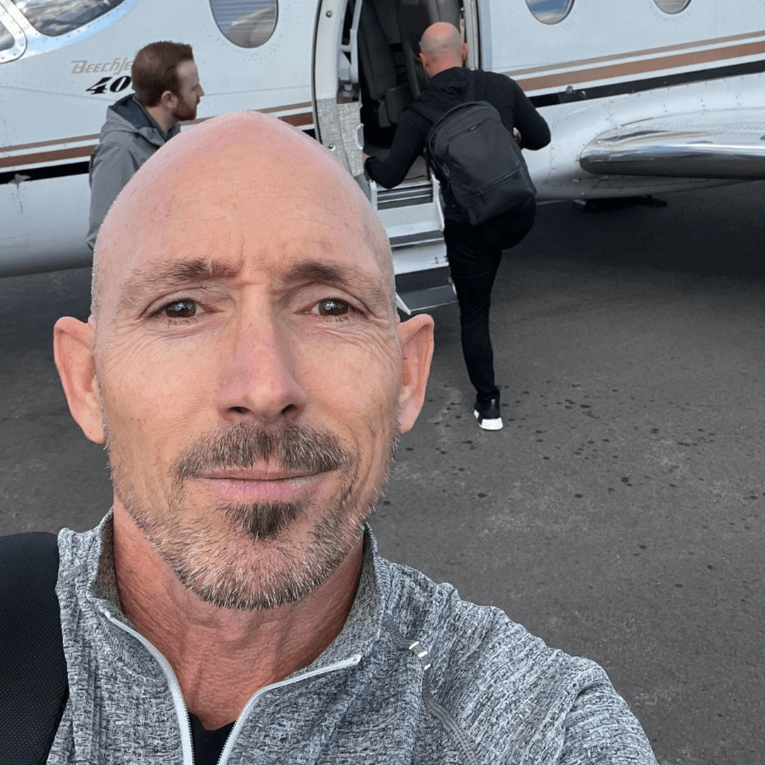 OrthoHeaven A man takes a selfie in front of a small jet branded with OrthoHeaven, while two other men board the aircraft in the background. Freedom Mapping