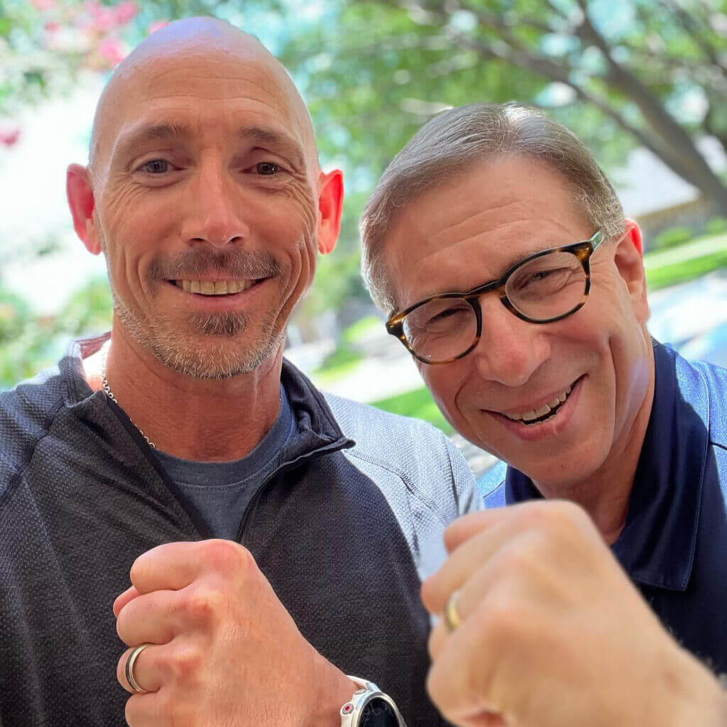 OrthoHeaven Two men standing outdoors smiling at the camera, both holding up their fists in a friendly gesture, showing their OrthoHeaven spirit. Freedom Mapping