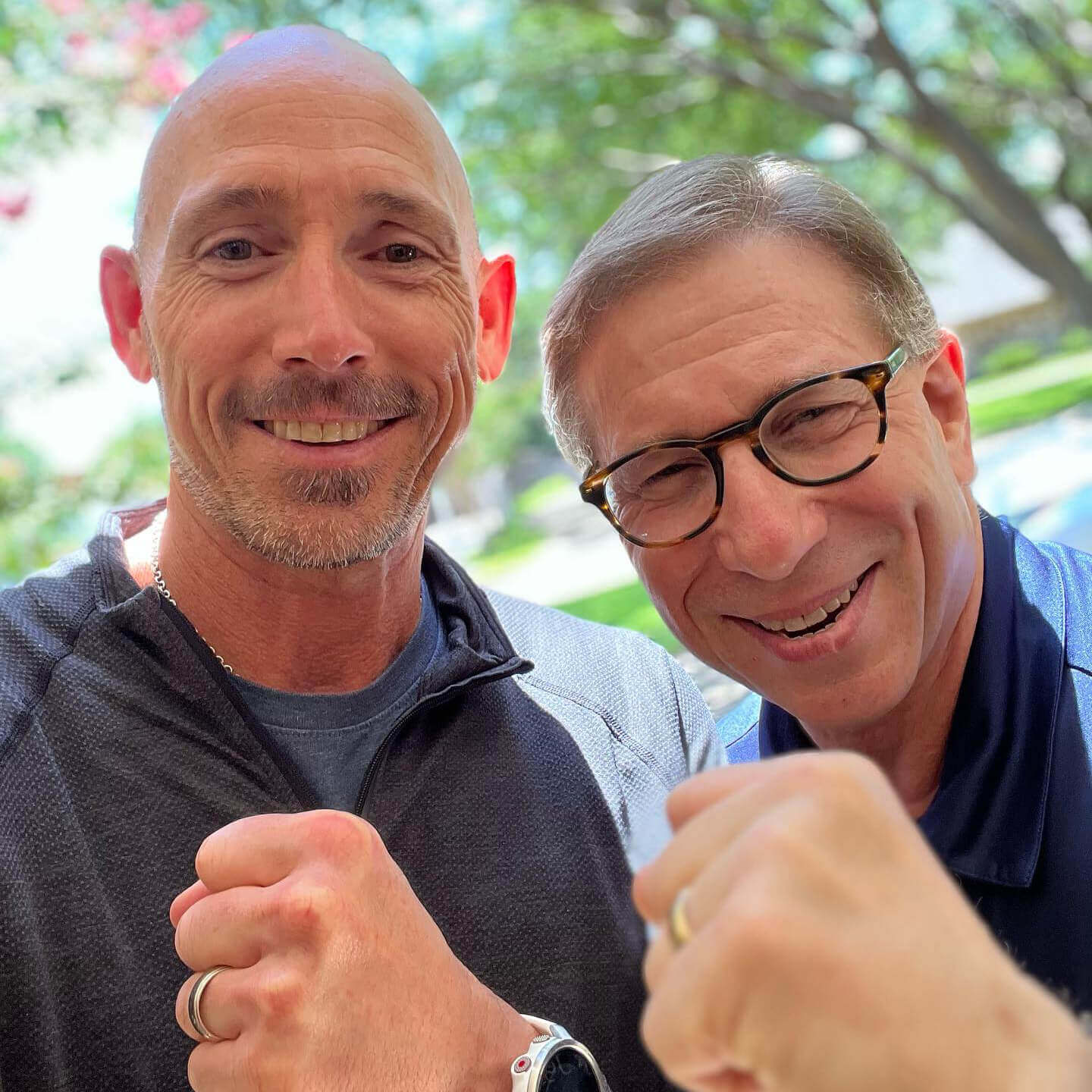 OrthoHeaven Two men standing outdoors smiling at the camera, both holding up their fists in a friendly gesture, showing their OrthoHeaven spirit. Freedom Mapping