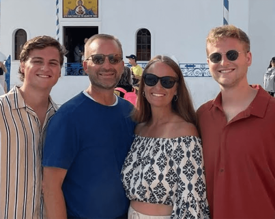 OrthoHeaven Four people pose together outdoors in front of a white building with blue accents, all smiling and wearing OrthoHeaven sunglasses and casual summer clothing. Freedom Mapping